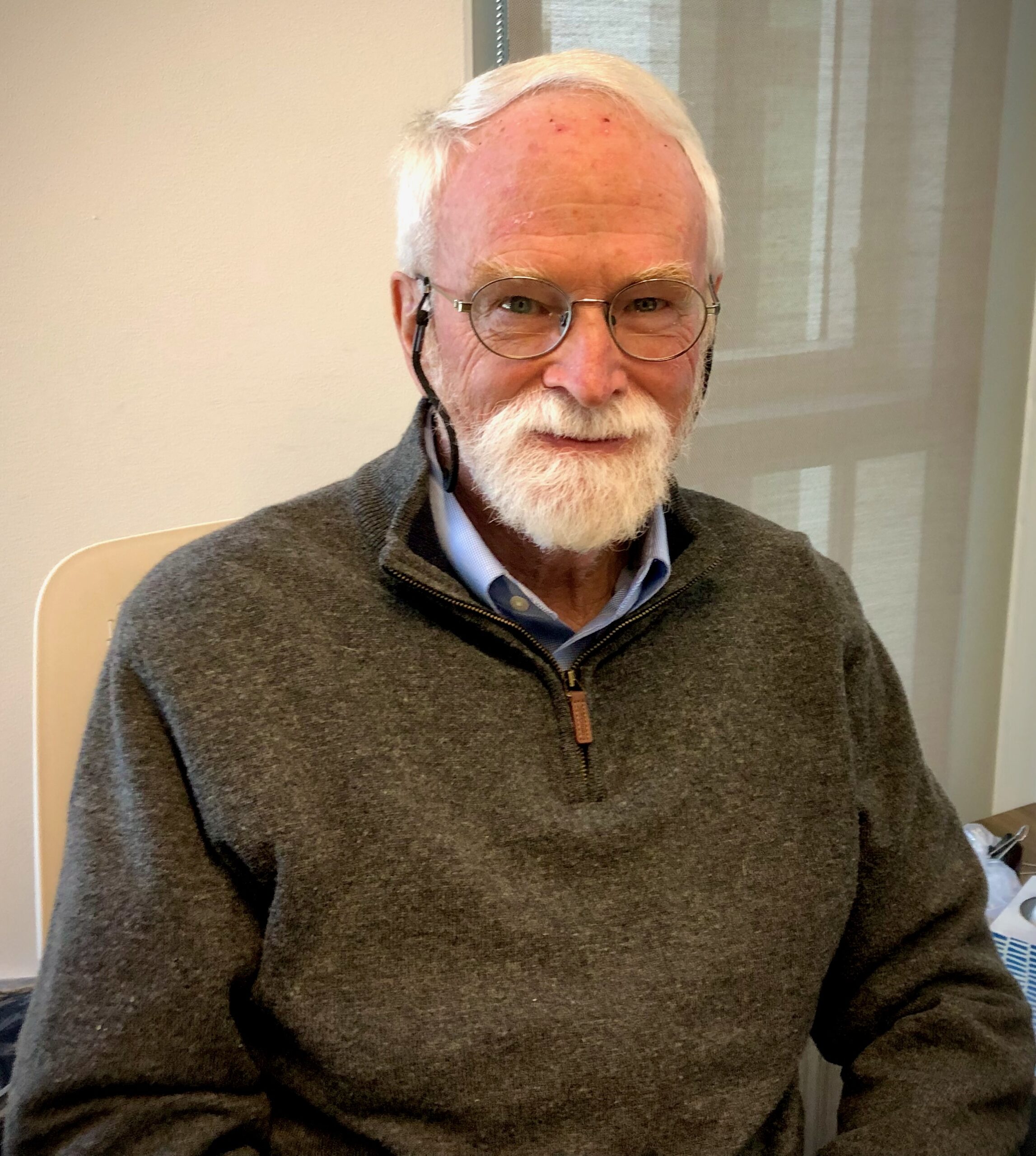 Law professor with white beard and glasses poses in office.
